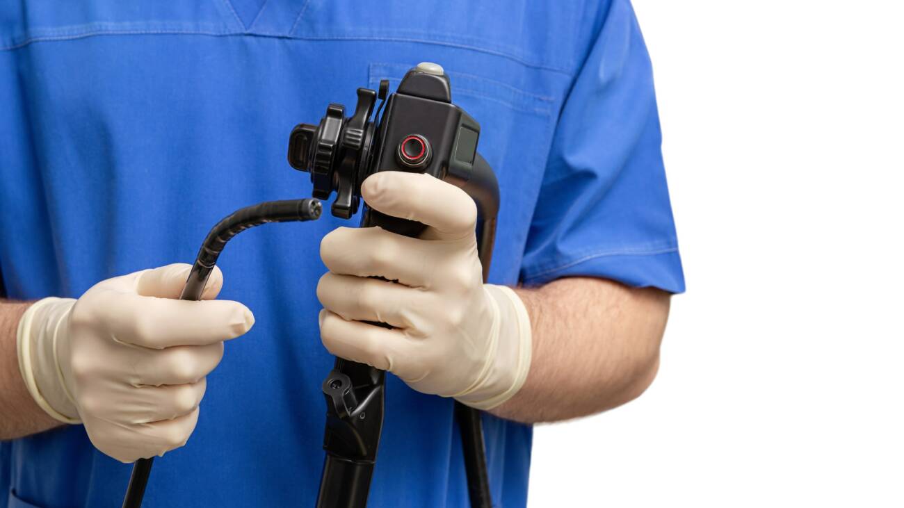 medical person in scrubs and rubber gloves holding a robotic surgical device